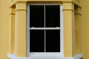 A yellow house featuring a white UPVC sliding sash window, showcasing a bright and inviting exterior.